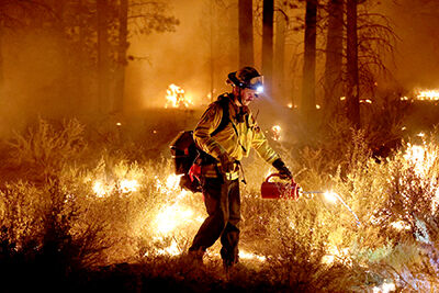 A firefighter sets a backfire